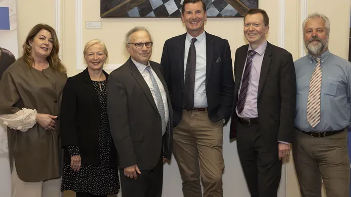 Six smartly dressed people stand in a line looking frowards.