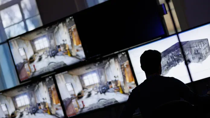 Vincenzo Rinaldi sits in front of several computer monitors showing virtual reality reconstructions of crime scenes