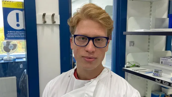 A head and shoulders photo of a man in a lab wearing a lab coat