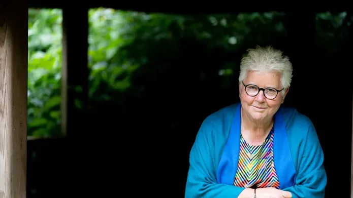 Val McDermid in a blue cardigan and striped, multi-coloured top, smiling