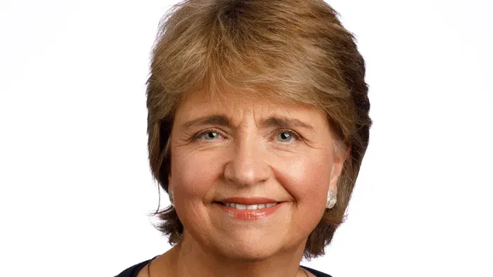 close up head and shoulders image of woman with short fair hair, smiling at camera