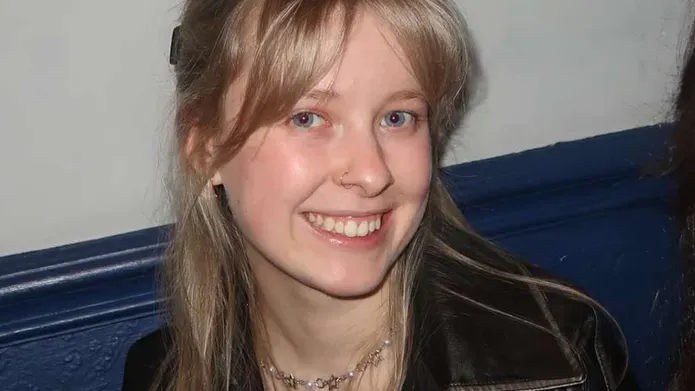 A smiling girl with blonde hair and a nose ring.