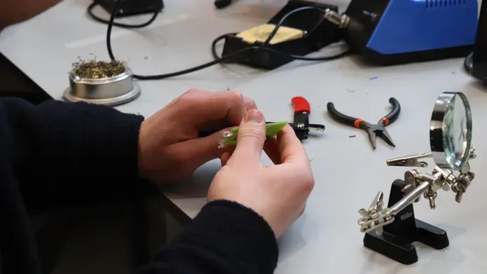 Undergraduate engineering student at the University of Dundee building components for PCB in a laboratory setting.