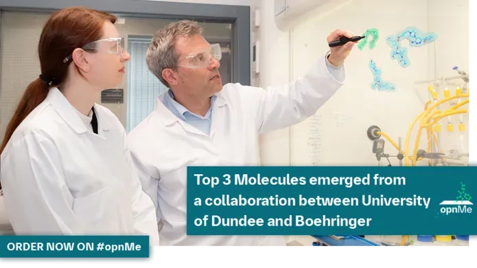 A man wearing a white lab coat and safety specs writing on a chemistry laboratory hood glass screen while a woman in white lab coat and safety specs looks on
