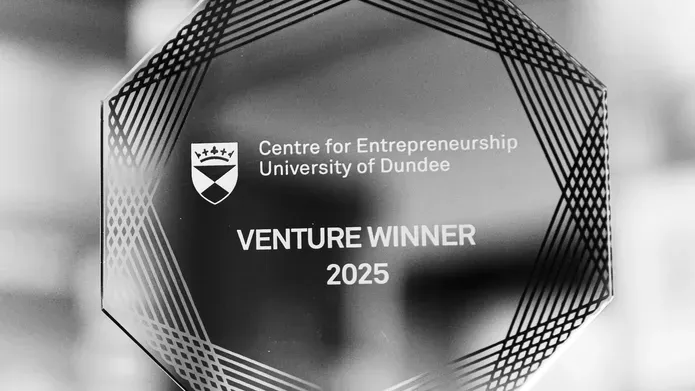 A black and white image of a Venture 2025 trophy, close-up