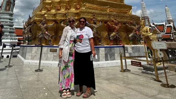 Two women stand in front of a large gold statue