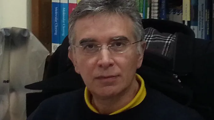 A headshot of Professor Vassilis Gorgoulis sitting in front of a row of books.