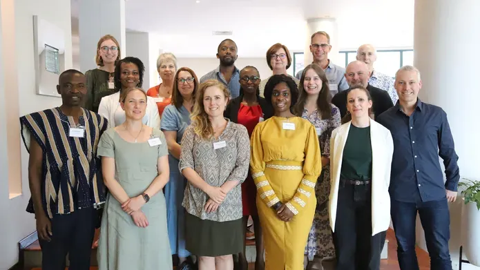 large group of people wearing smart clothes and standing grouped together. looking and smiling at camera