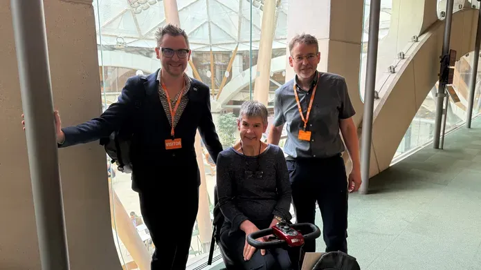 Dr Tom Griffiths, Professor Annalu Waller and Rohan Slaughter stand next to one another in a corridor