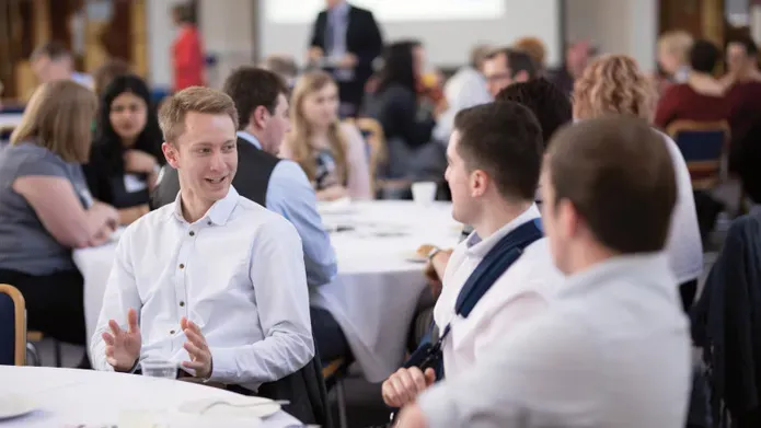 Students sitting discussing ideas at a table as part of an event