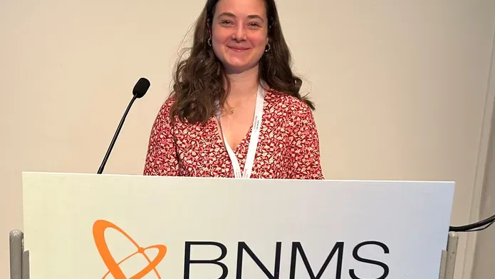 Abby Lang standing at a podium with a BNMS banner posted at the front of the podium