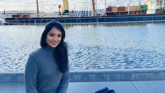 Pavithra Sundaravaradan sitting outside the V&A museum with the Discovery ship in the background