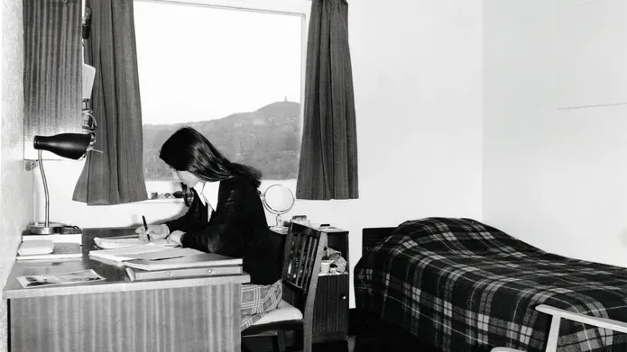 A student sits at a desk in university accommodation in the 1970s