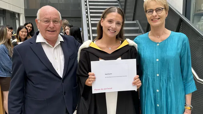 Three people stood next each other, one holding a certificate