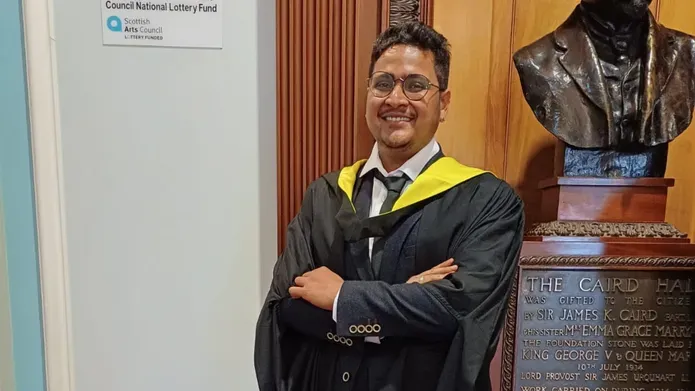 Supratim Das Gupta standing inside Caird Hall in his graduation gown