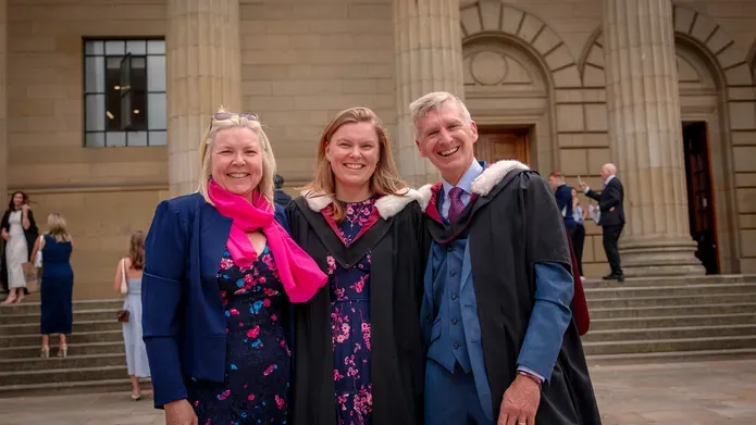 a group of three stood outside smiling