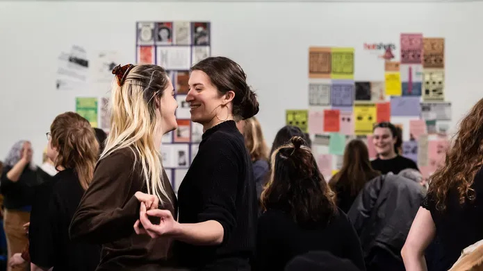 Two white people dancing in a crowded gallery