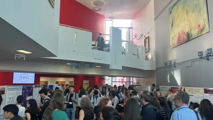 A crowd of people all stood together in a foyer with an overlooking mezzanine level above