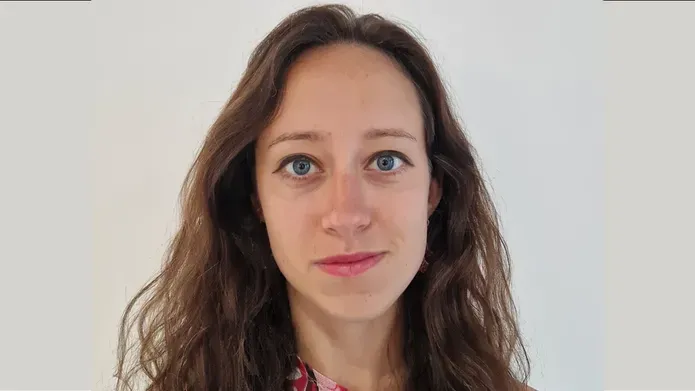 A headshot of a woman with long brown hair smiling