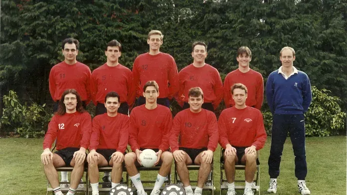 Paul McPate stand at the far right, top row with the University football team and their trophies