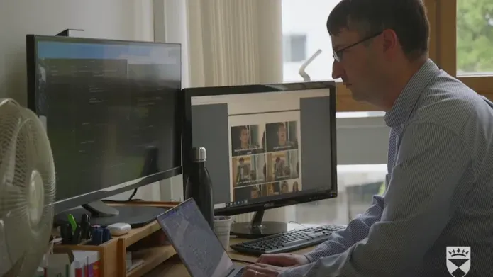 A research sitting at his desk in front of two computer screens 