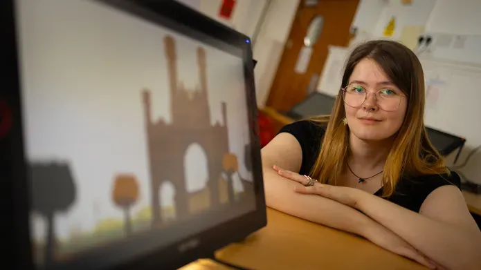 Young woman with dark hair shown to the side of a computer screen with a graphic of an arch on it