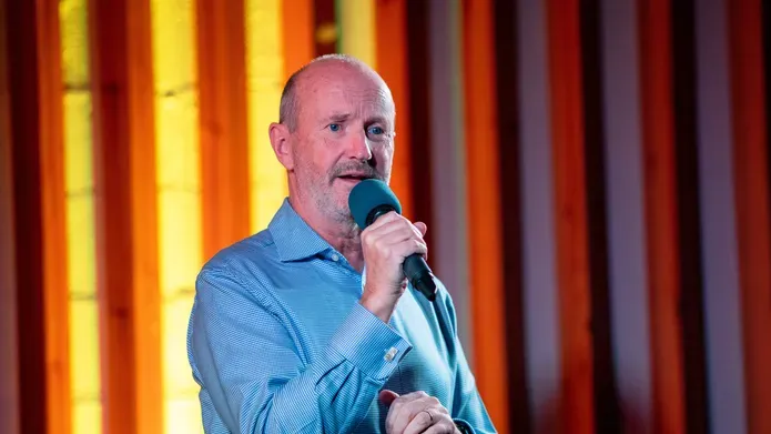 Comedian Fred MacAulay performing on stage, holding a microphone