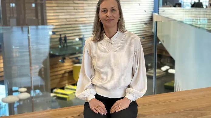 woman with white shirt on and black skirt, sitting on a bench which is on a mezzanine balcony 