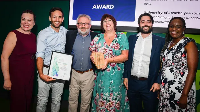 The Dundee team with their award, against a branded backdrop