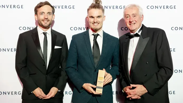 Nathan Dudley, Create Change Challenge winner, with David McBeth and Brian McNichol of the University, with award standing infront of a branded backdrop