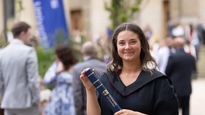 Woman in graduation gown holding a scroll