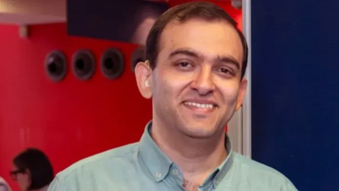 Abdullah Alagha, wearing a green-collared shirt, smiling