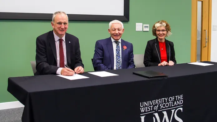 two woman and a man sat in a line at a table smiling