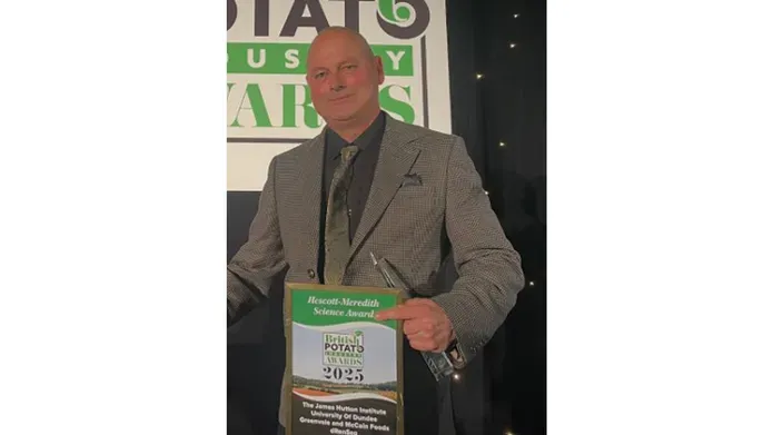 A man smiling while holding an award