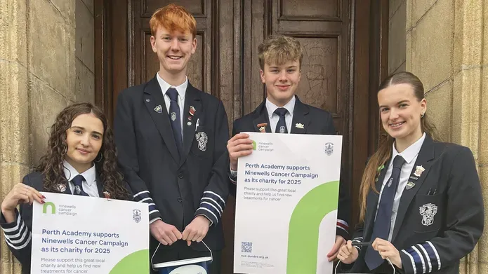 A group of four students at Perth Academy holding fundraising posters and charity buckets