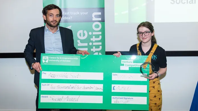 Brian McNicoll and Amy Winter hold a large cheque at the Venture 2025 awards event