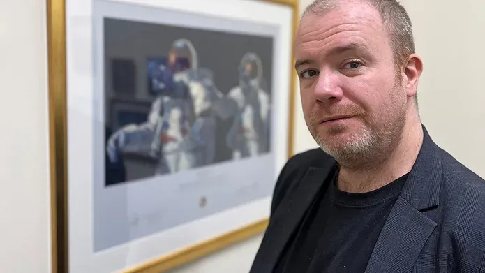 Dr Simmonds standing infront of an image of astronauts