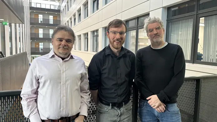 Three men stood side by side smiling