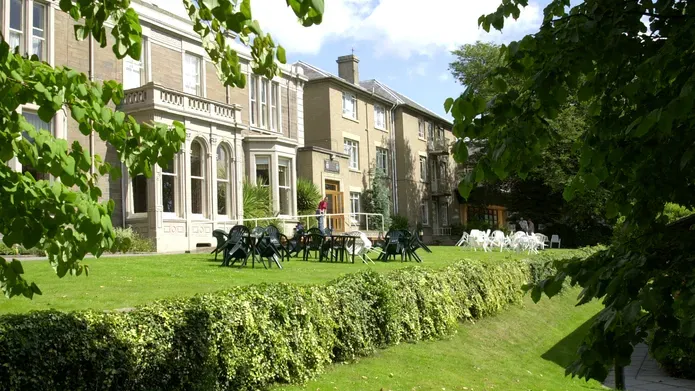 Outside of West Park Halls with a rolling lawn and white chairs around a table