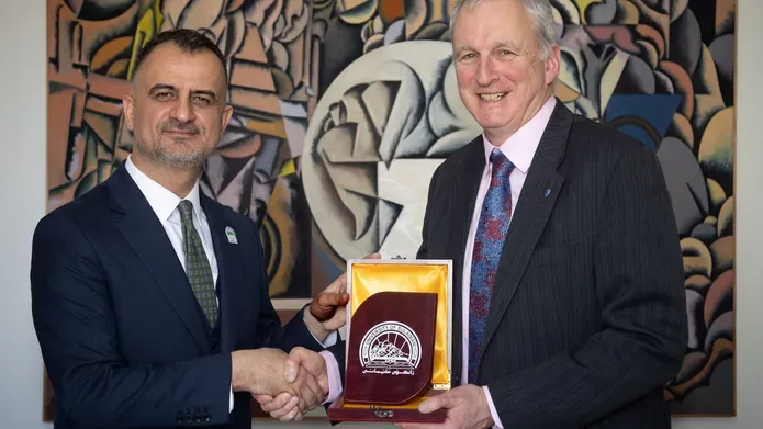 Asst. Prof. Dr. Ranjdar Mahmood Osman and Professor Seaton shaking hands holding a medal with the University of Sulaimani crest 