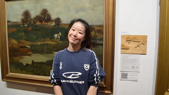 PhD student Eevee han stands in front of the exhibition that hs ehas helped create which showcases her research into accessible public art