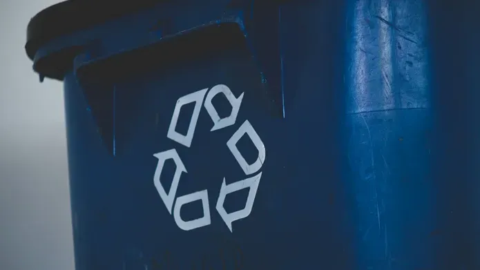 A recycling symbol on the front of a green bin