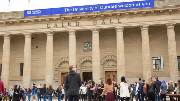 An exterior view of the Caird Hall on a sunny day, with graduates in the city square.