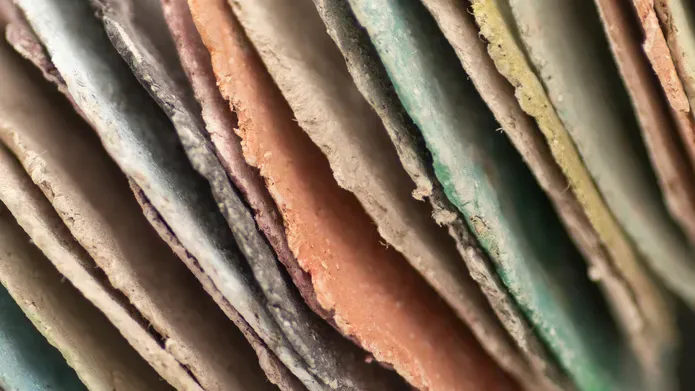 Artwork as part of the DJCAD Masters Showcase of an abstract sculpture of stacked, hand-cut coloured paper discs forming curved, tubular loops with textured edges