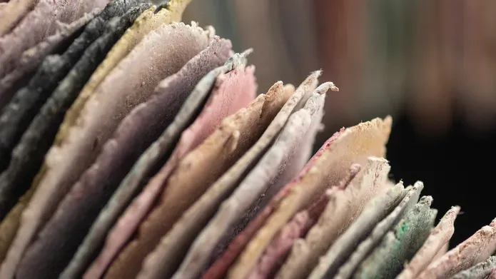Artwork as part of the DJCAD Masters Showcase of an abstract sculpture of stacked, hand-cut coloured paper discs forming curved, tubular loops with textured edges