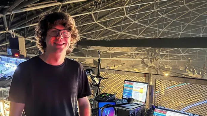 Lewis, standing on the left of the image, infront of an empty OVO Hydro arena