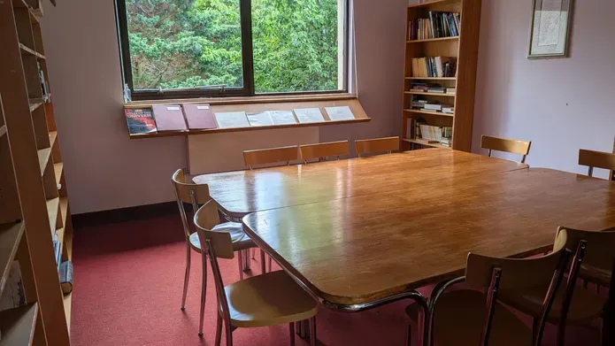 A large table with several chairs located in the Chaplaincy