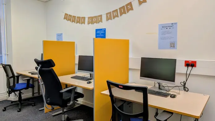 A small room with height-adjustable desks, ergonomic chairs and printers