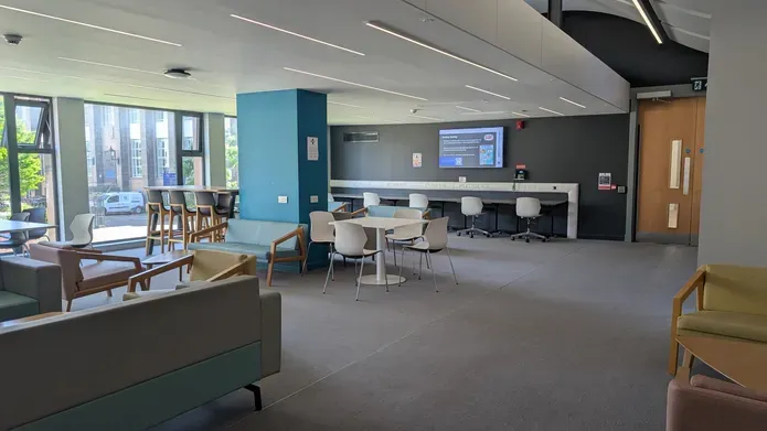 A large room with high stools, cafe seating and soft chairs.