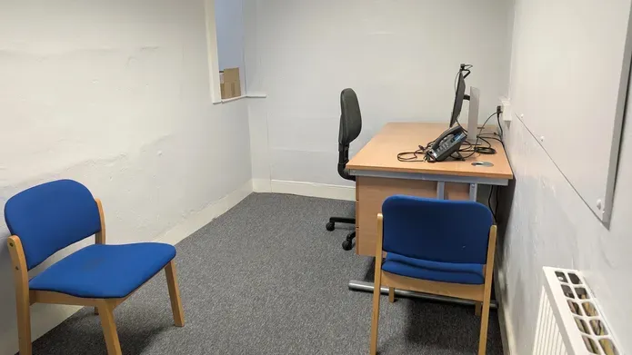 A small room with an office chair, table and computer
